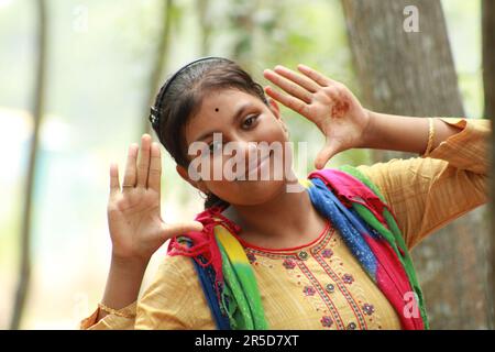 Nahaufnahme eines indischen Teenagers, das über den Naturhintergrund in die Kamera schaut. Stockfoto