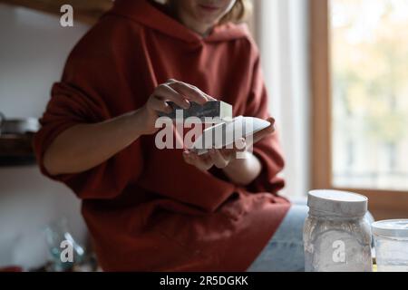 Hands Woman Besitzer Töpferwerkstatt, die handgemachte Gerichte aus natürlicher Töpferei mit Schleifstein herstellt Stockfoto