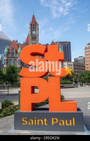 Farbenfrohes orangefarbenes Schild für St. Paul in Rice Park mit dem historischen Landmark Center, erbaut im Jahr 1902 mit dem Uhrenturm im Hintergrund; St. Paul, Minnie. Stockfoto