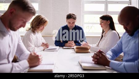 Gruppe von Jungen multiethnischen Menschen Lesen der Bibel über Holz- Schreibtisch Stockfoto