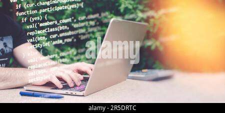 Mann, der im Garten an einem Notebook arbeitet. Nahaufnahme männlicher Hände, die am Computer tippen Stockfoto