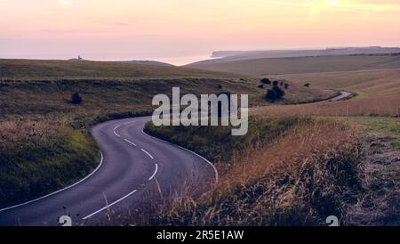 Beachy Head Z-Biegungen. Eine kurvenreiche Straße in East Sussex mit dem Leuchtturm Belle Tout und dem Ärmelkanal in der Ferne. Stockfoto