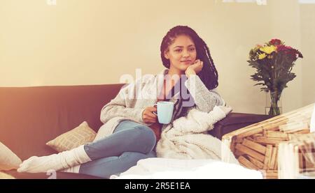 Ich brauche meinen Freiraum, so wie ich Luft zum Atmen brauche. Eine junge Frau, die eine Tasse Kaffee in ihrem Wohnzimmer genießt. Stockfoto