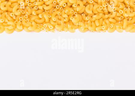 Ungekochte Chifferi Rigati Pasta auf dem weißen Tisch. Fett und ungesunde Lebensmittel. Klassische Trockene Makkaroni. Italienische Kultur und Küche. Rohe Pasta Stockfoto