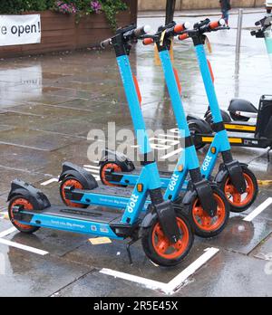 LONDON, Großbritannien - 21. JUNI 2021: Drei blaue Dott-Elektroroller parken auf Asphalt in Kensington. Dott ist ein umweltfreundlicher sol für Mikromobilität Stockfoto