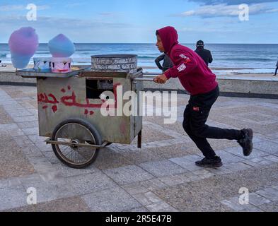 Sousse, Tunesien, 22. Januar 2023: Ein tunesischer Zuckerwatte-Verkäufer läuft mit seinem Handwagen auf der Suche nach Kunden entlang der Strandpromenade Stockfoto