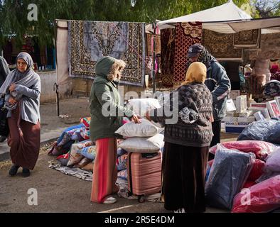 Sousse, Tunesien, 22. Januar 2023: Kunden untersuchen die Waren an einem Verkaufsstand, der Kissen, Bettwäsche und Teppiche auf dem lokalen Markt in Sousse verkauft Stockfoto