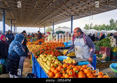 Sousse, Tunesien, 22. Januar 2023: Kunden untersuchen die Waren in einem Verkaufsstand, der Orangen, Äpfel, Zitronen und andere Früchte auf dem lokalen Markt in Souss verkauft Stockfoto