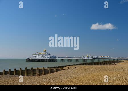 Eastbourne Pier im Sommer mit blauem Himmel und ruhigem Meer. Kiesstrand und Groyne im Vordergrund. Stockfoto