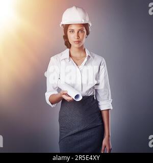 Erfolg im Aufbau. Porträt eines gut gekleideten Bauingenieurs, der posiert, während er Baupläne im Studio hält. Stockfoto