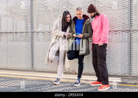 Drei glückliche junge Freunde, die gerne telefonieren Stockfoto
