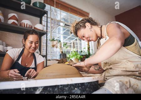 Der Weg zur Erfüllung ist mit Kunst gepflastert. Zwei junge Frauen, die mit Ton in einem Töpferstudio arbeiten. Stockfoto