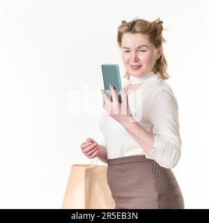Glückliche Shopaholic-Frauen, die ihr Handy benutzen, um zu bezahlen. Black Friday und Online-Shopping-Konzept. 49 Jahre alte lächelnde Kaufinteressentin in Weiß Stockfoto