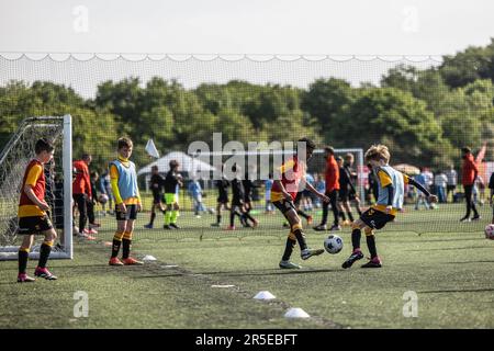 Jungen, die an sonnigen Tagen in Großbritannien Fußball und Basketball organisieren. Stockfoto