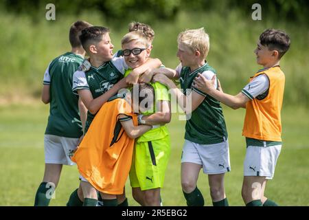 Jungen, die an sonnigen Tagen in Großbritannien Fußball und Basketball organisieren. Stockfoto