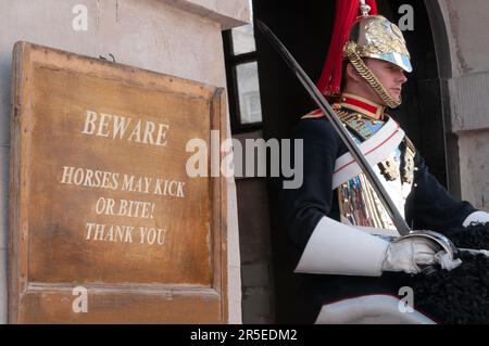 London, Großbritannien - 03. Juni 2023 - Gefahrenschild neben einem von der Kavallerie montierten Soldaten des Regiments Stockfoto