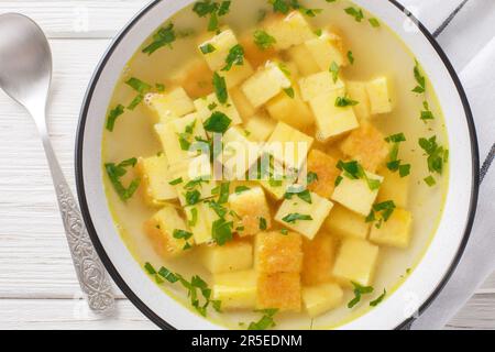Zuppa imperiale italienische Suppe aus Hühnerbrühe mit Parmesan-Eierknödeln auf dem Teller auf dem Tisch. Horizontale Draufsicht von oben Stockfoto