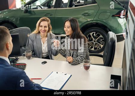 Glückliches weibliches LGBT-Paar beantragt einen Autokredit Stockfoto