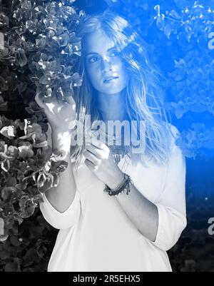 Jeder Tag ist schön, wenn man in der Natur ist. Schwarzweißfoto einer attraktiven jungen Frau, die unter einem blühenden Baum steht. Stockfoto