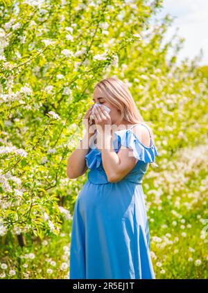 Eine schwangere Frau im Garten blühender Apfelbäume ist allergisch. Selektiver Fokus. Die Natur. Stockfoto