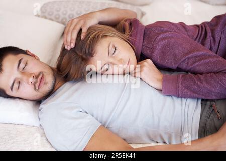 Zu Hause ein Nickerchen machen. Attraktives junges Paar, das zu Hause zusammen liegt. Stockfoto