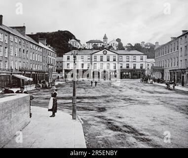 Ein Blick aus dem späten 19. Jahrhundert auf den Platz in Fermoy, einer Stadt am Fluss Blackwater in der Grafschaft Cork, Irland. Im Jahr 1791 wurden die Grundstücke um Fermoy von einem Schotten, John Anderson, gekauft, einem Unternehmer, der die Straßen entwickelte und das Postbussystem in Irland startete. Er entwarf die Stadt und die Straßen sind weitgehend die gleichen, wie sie ursprünglich gebaut wurden. Stockfoto