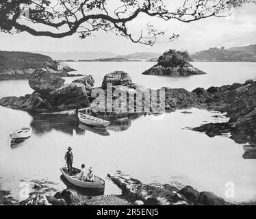 Ein Blick aus dem späten 19. Jahrhundert auf Touristen und einen Bootsmann neben Otter Island in Bantry Bay in der Nähe von Glengarriff, einem Dorf auf der Beara-Halbinsel in County Cork, Irland. Stockfoto