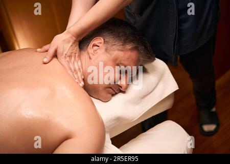 Qualifizierter Massagetherapeut mit miofaszialer Freisetzungstechnik an der Kundenwirbelsäule Stockfoto