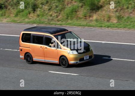 2006 Orange Black NISSAN SERENA 2000cc Fensterbus; Fahrt mit hoher Geschwindigkeit auf der Autobahn M6 im Großraum Manchester, Großbritannien Stockfoto