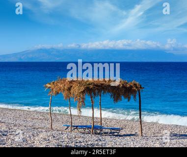 Sommer morgen kiesiger Strand mit Sonnenliegen und Baldachin (Albanien). Stockfoto