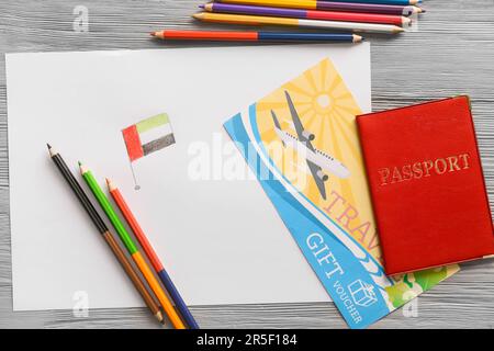 Papierbogen mit gezogener Flagge der VAE, Bleistifte, Geschenkgutschein und Reisepass auf grauem Holzhintergrund Stockfoto
