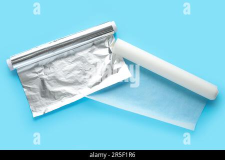 Backpapierrollen und Aluminiumfolie auf farbigem Hintergrund Stockfoto