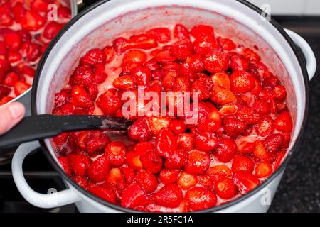 Großer Topf mit dampfender Erdbeermarmelade. Konservierung von Beeren und Früchten. Stockfoto
