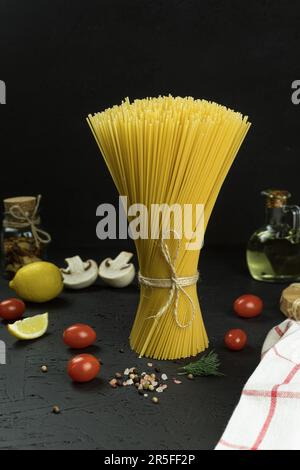 Rohe und frische hausgemachte Pasta auf dem Tisch, Nahaufnahme. Kochkonzept. Seitenansicht auf dunklem Hintergrund. Speicherplatz kopieren Stockfoto