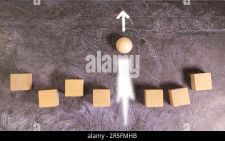 Golfball und hölzernes T-Shirt fliegen in einer Sandwolke auf schwarzem Hintergrund. Stockfoto