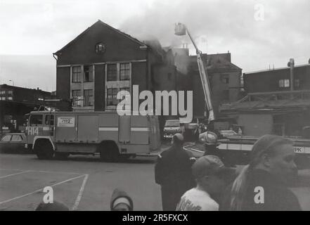 Feuerwehr Helsinki Water Tender (H14) und Drehteller-LKW (H76) bei einem Brand in Sörnäinen, ca. 1996. Im Hintergrund wird der Brand von Hubarbeitsbühnen aus bekämpft. Stockfoto