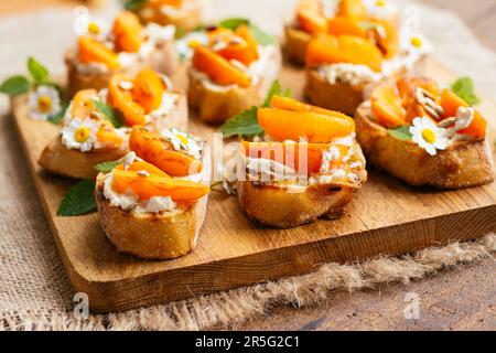 Schneidebrett mit hausgemachter Aprikose auf veganem Frischkäse-Bruschetta. Stockfoto