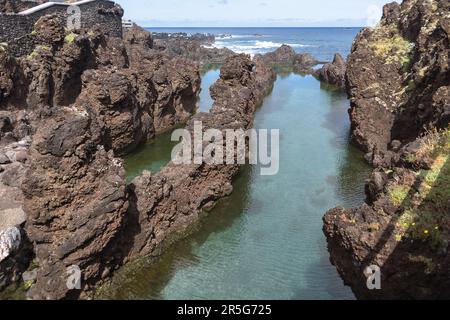 Madeira Island Portugal - 04 19 2023 Uhr: Blick auf die natürlichen Pools im Dorf Porto Moniz, geformt durch vulkanische Felsen, Insel Mole im Hintergrund, Stockfoto