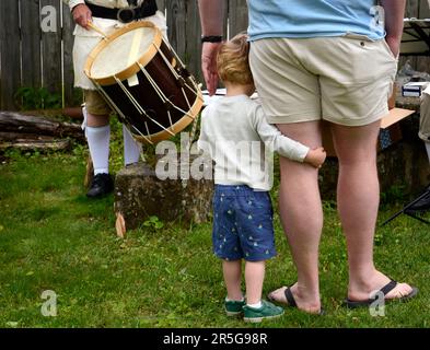 Ein Vater und sein junger Sohn hören sich ein Trommel- und Fifenkonzert bei einer lebendigen Geschichtsnachstellung in Abingdon, Virginia, an. Stockfoto