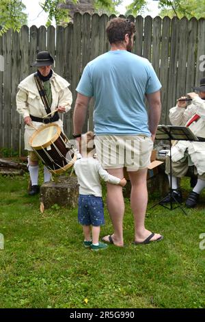 Ein Vater und sein junger Sohn hören sich ein Trommel- und Fifenkonzert bei einer lebendigen Geschichtsnachstellung in Abingdon, Virginia, an. Stockfoto