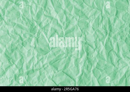 Zerknitterter, hellgrüner Papierhintergrund aus recyceltem Papier. Abstrakter Hintergrund mit zerknittertem und faltenförmigem Hintergrund, Hintergrundbild mit Kopierbereich, Draufsicht. Stockfoto