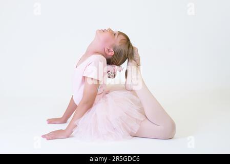 Kleine Ballerina-Tänzerin in einer pinkfarbenen Tutu-Akademie-Studentin, die auf weißem Hintergrund posiert Stockfoto