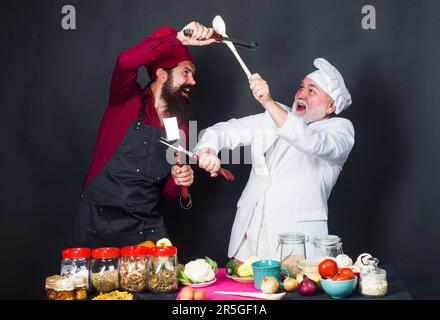 Kulinarische Schlacht mit professionellem Koch. Zwei Köche in Uniform in der Küche konkurrieren in der kulinarischen Show. Die Küche ist super. Kochwettbewerb. Zwei Koch oder Bäcker Stockfoto