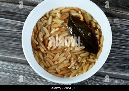 Nahöstliche ägyptische Pasta-Suppe, auch bekannt als Shorbet Lesan El Asfour, traditionelle ägyptische Komfortgerichte aus Orzo Pasta, Butter und Oliven Stockfoto