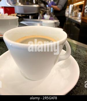 Eine fesselnde Nahaufnahme eines frisch gebrühten Americano-Kaffees, zubereitet in einem italienischen Café. Das Bild zeigt einen perfekt gegossenen Kaffee in einem Styl Stockfoto