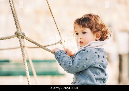 Außenporträt eines niedlichen Kleinkindes, das Spaß auf dem Spielplatz hat, 1 bis 2 Jahre altes Kind, das im Park spielt Stockfoto