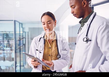 Sie bekommt eine zweite Meinung. Zwei junge Ärzte arbeiten an einem digitalen Tablet, während sie im Krankenhaus stehen. Stockfoto