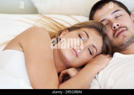 Gemeinsam träumen. Attraktives, junges Paar, das im Bett schläft. Stockfoto
