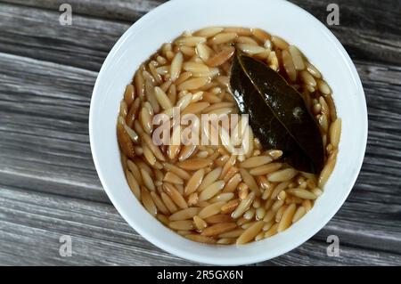 Nahöstliche ägyptische Pasta-Suppe, auch bekannt als Shorbet Lesan El Asfour, traditionelle ägyptische Komfortgerichte aus Orzo Pasta, Butter und Oliven Stockfoto