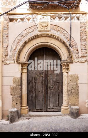 Alte, mittelalterliche Holztüren mit Steinbögen und Wappen darüber in Segovia, Spanien. Stockfoto